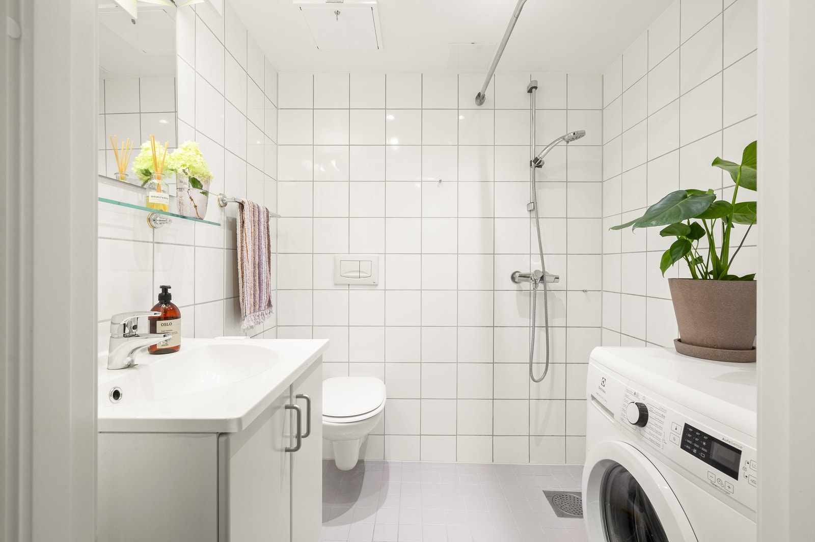 Badet er pent flislagt på gulv og vegger med varme i gulvet. Badet har dusjhjørne med forheng og vegghengt klosett. Det er opplegg for vaskemaskin. Galleribilde