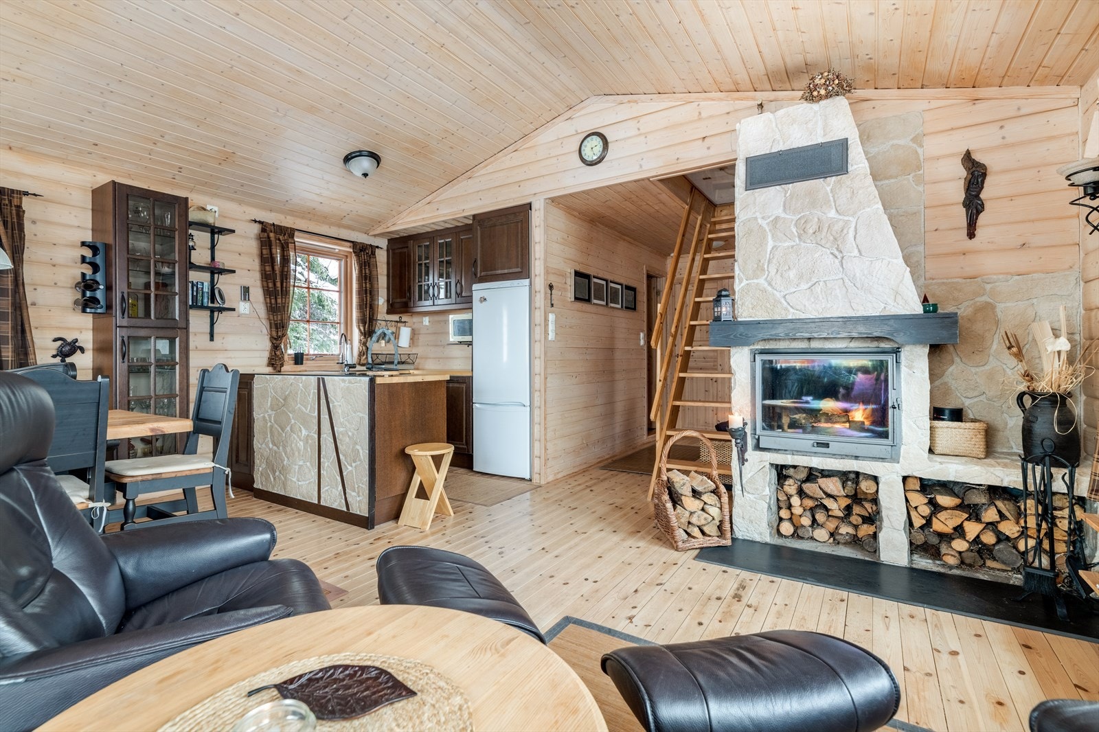 Hytta har en koselig stue med åpen løsning mot kjøkkenet. God takhøyde gir en fin følelse av åpenhet, og store vindusflater tilfører rikelig med dagslys. Galleribilde