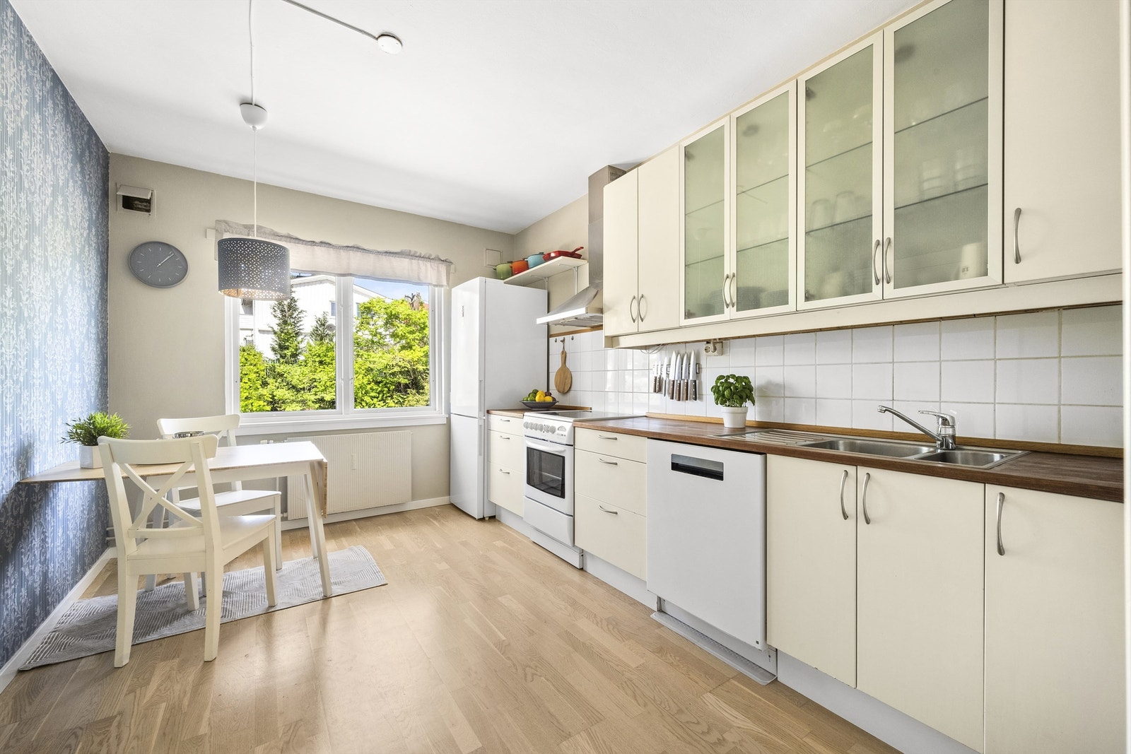 Kjøkkenet utstyrt med frittstående hvitevarer: Komfyr med platetopp, oppvaskmaskin og kjøleskap med fryser. Vegghengt ventilator med kullfilter Galleribilde