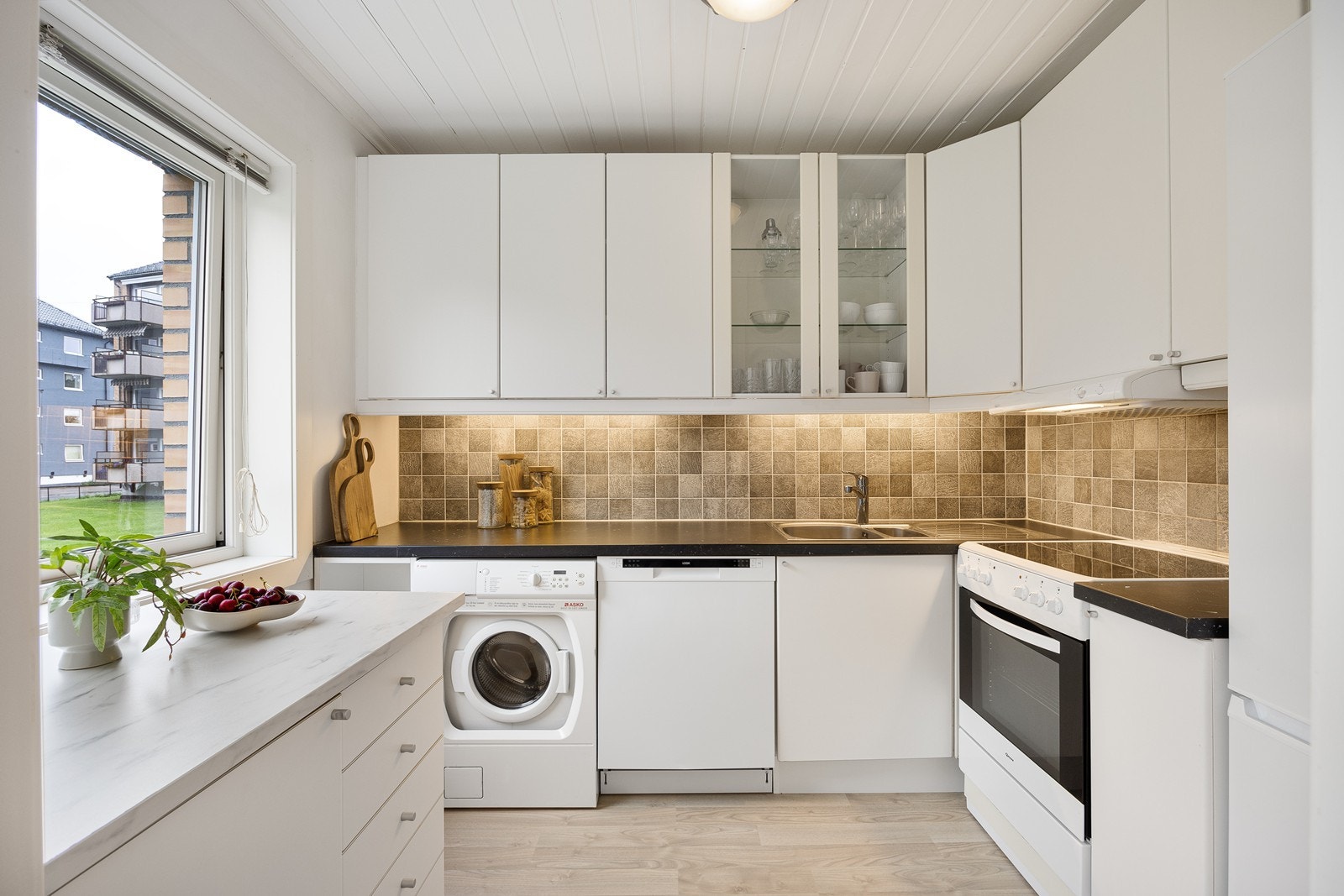 Kjøkkenet ligger i eget rom og har en praktisk og arealeffektiv vinkelform.
I tillegg er det under vinduet etablert ekstra skuffeløsning. Galleribilde