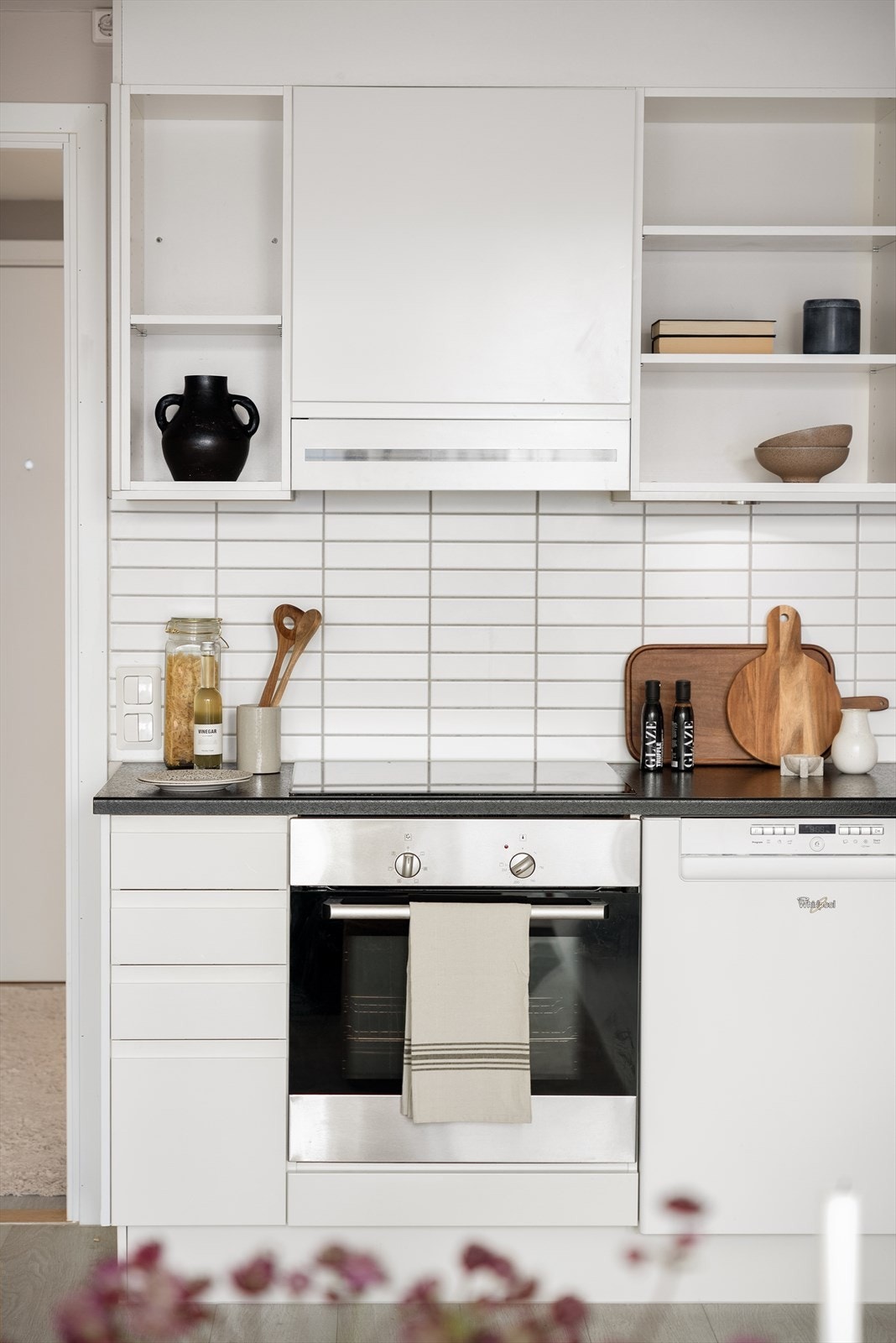Integrerte hvitevarer med oppvaskmaskin, stekeovn og induksjonstopp med ventilator over. Plass for frittstående kjøl/frys. Galleribilde