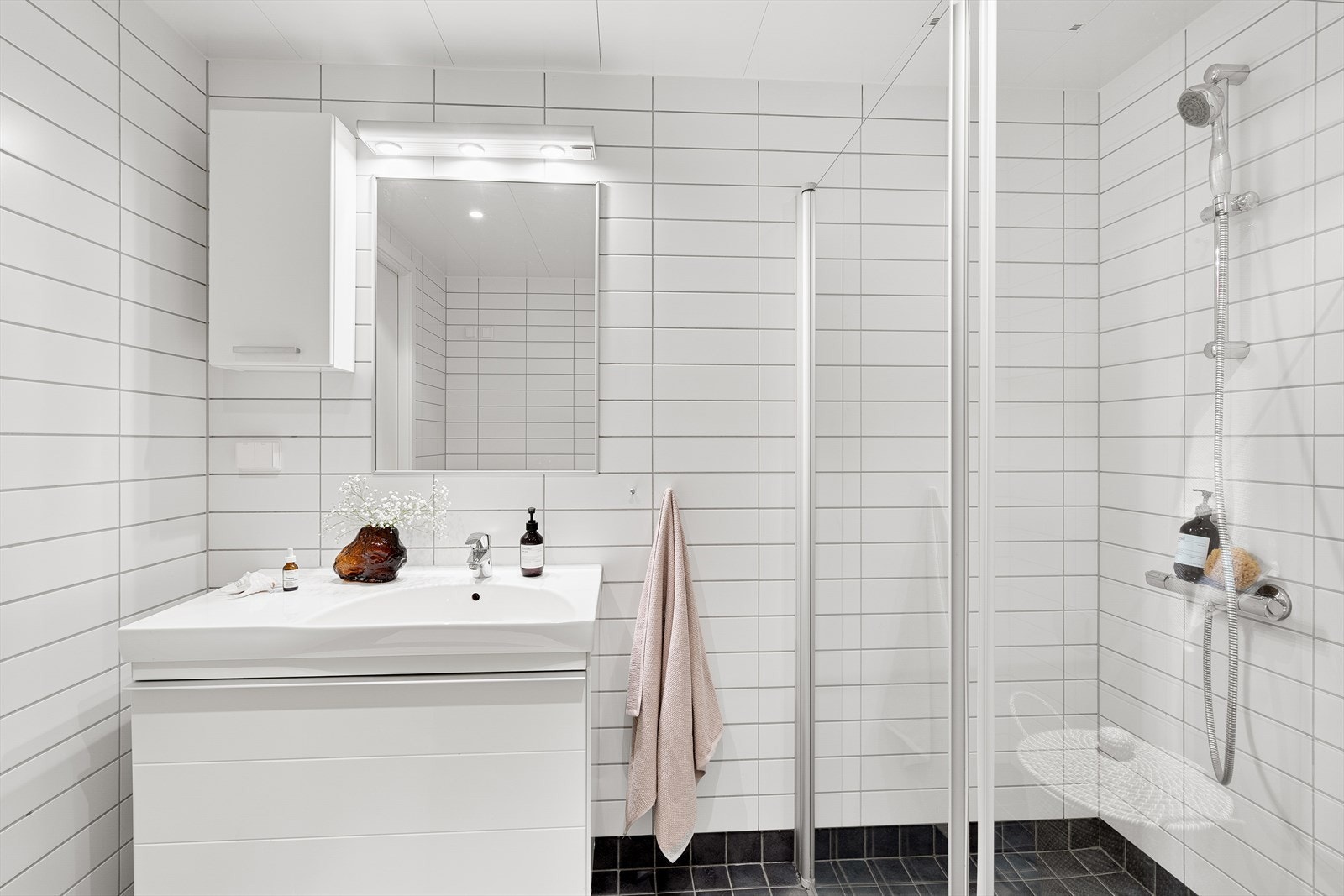 Baderomsinnredning med servant på underskap med speil, belysning og skap over. Galleribilde