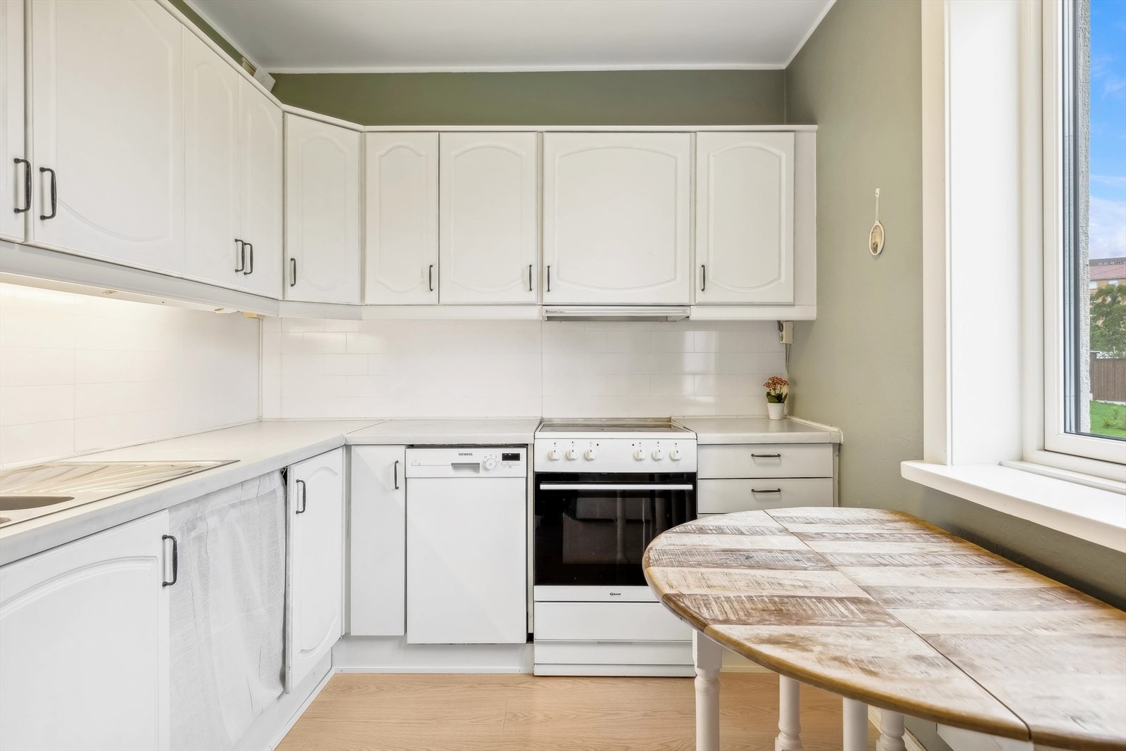 Kjøkkenet inneholder frittstående komfyr/platetopp, kjøl- og fryseskap og oppvaskmaskin Galleribilde