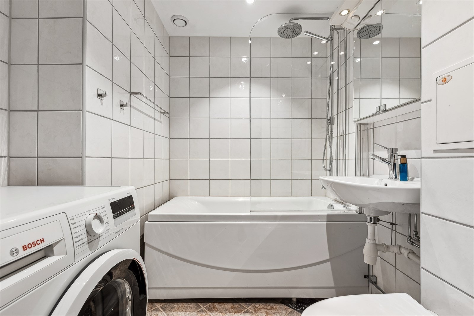 Badet er pent flislagt, har varmekabler i gulv og opplegg for vaskemaskin Galleribilde