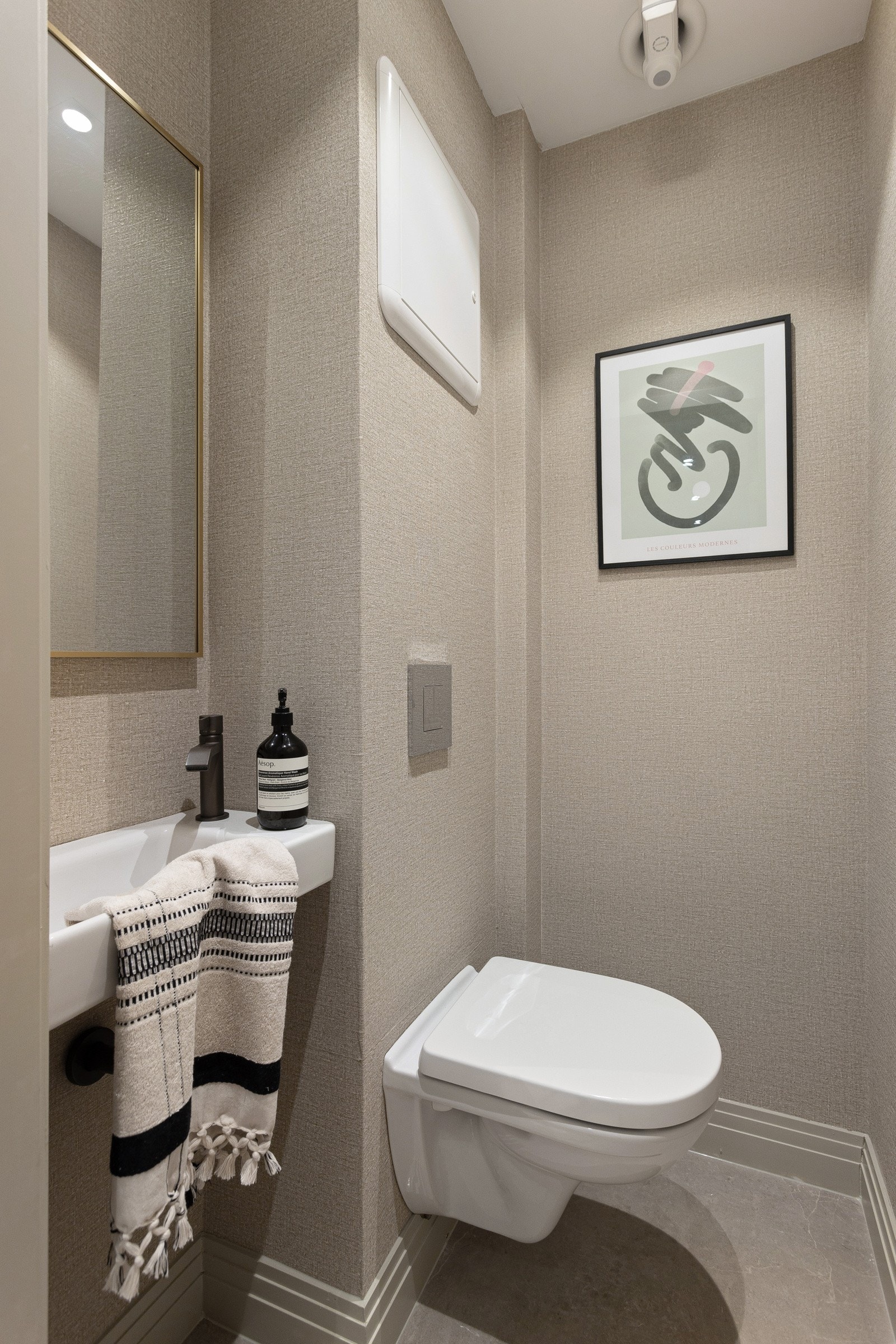 Toalettet har vegghengt wc, servant og fliser på gulv. Eksklusiv tapet fra Elitis på overflatene. Galleribilde