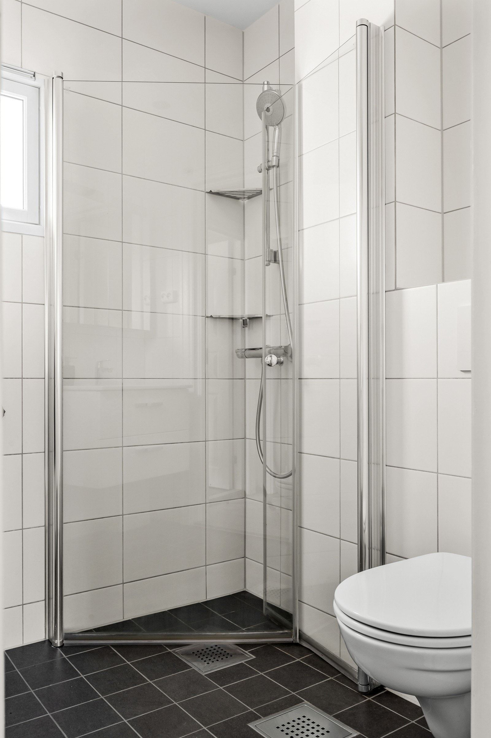 Dusjhjørne med praktisk innfellbare dører i glass. Hylleløsning i hjørnet for såpe. Galleribilde