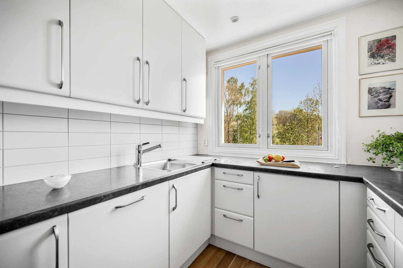 Kjøkkeninnredning fra 2012 med hvite glatte fronter og benkeplater av laminat med nedfelt oppvaskkum. Det er montert lekkasjevarsler på kjøkkenet. Her er det behagelig å stå og lage mat med varme i gulvet. Galleribilde