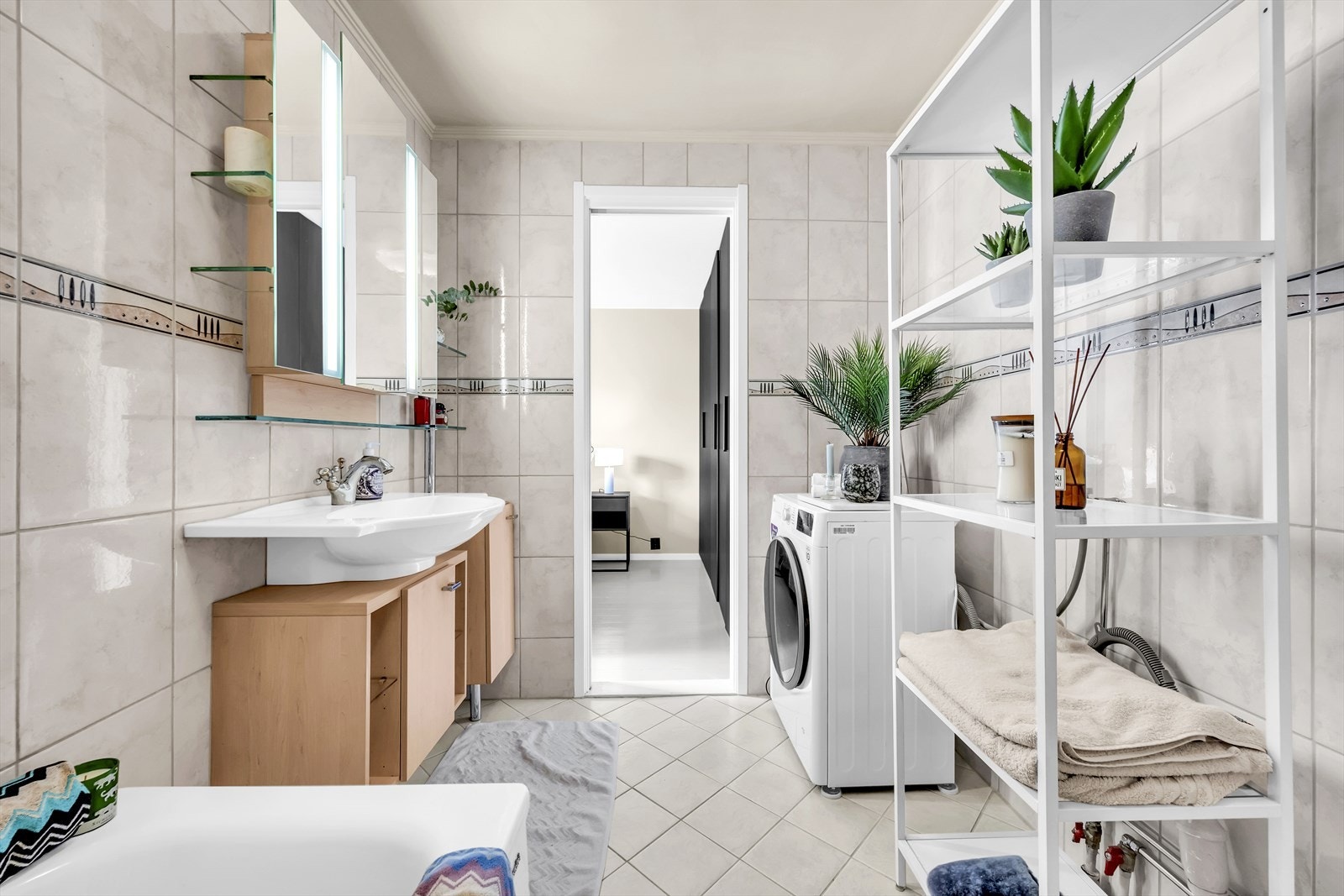 Badet er utstyrt med badekar med glassvegg, gulvstående toalett og servant med skapinnredning Galleribilde