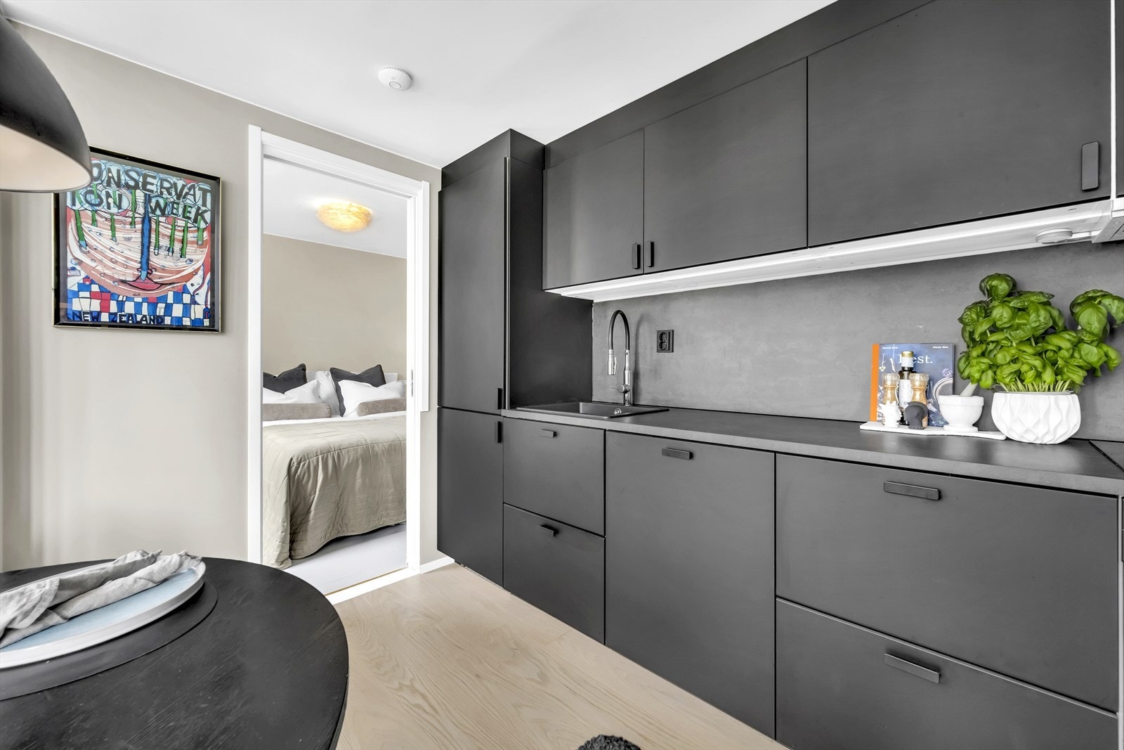 Smakfull innredning fra Ikea med glatte, mørke fronter, laminat backsplash over kjøkkenbenken og benkeplate i laminat Galleribilde
