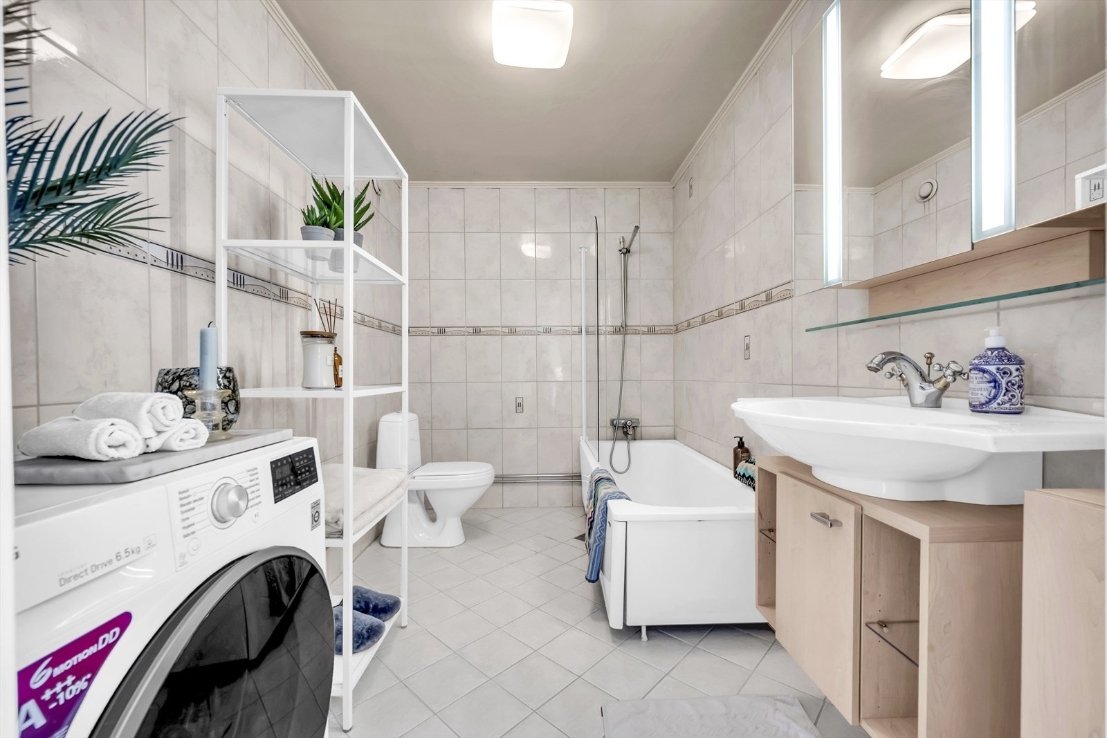 Stort bad med flislagte overflater, gulvvarme og opplegg for vaskemaskin Galleribilde