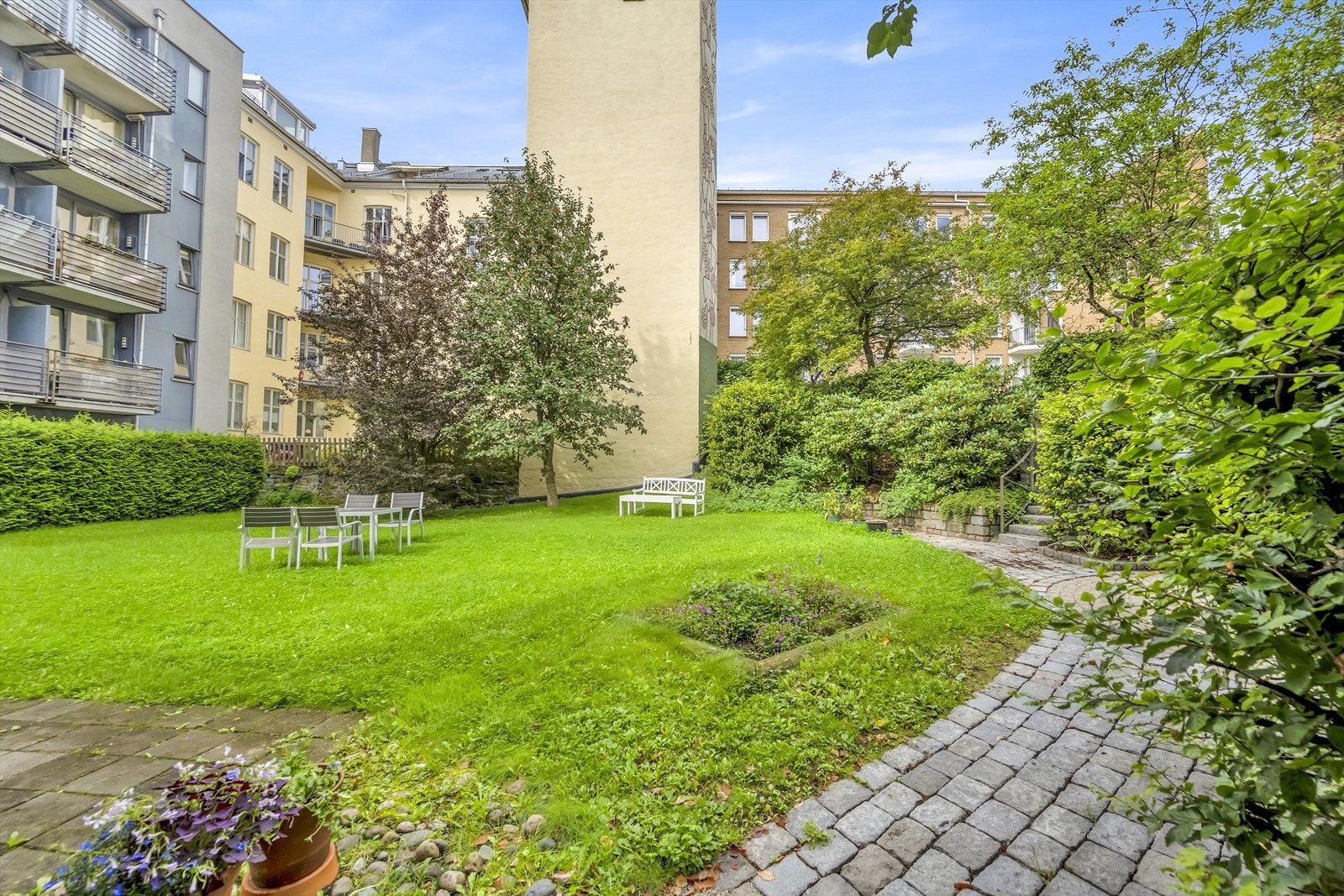 Pent opparbeidet bakgård med plen og beplanting. Flere hyggelige sittegrupper Galleribilde