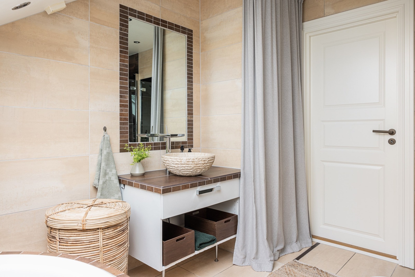 Lyst og pent flislagt bad med varme i gulv og downlights i skråhimling. Innredningen består av servantskap med skuffeinnredning, servant, speil over servant og vegghengt toalett. Galleribilde