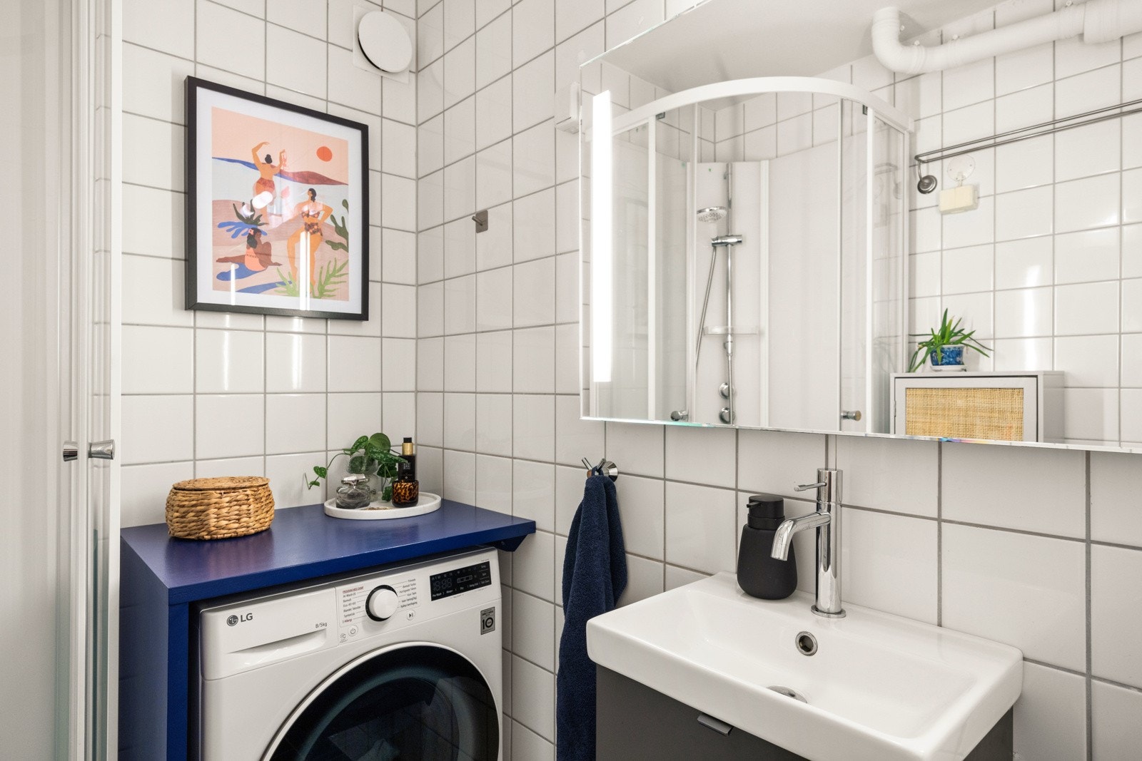 Innredet med vegghengt servantskap med ovenpåliggende servant, speil med integrert belysning, toalett, dusjkabinett og opplegg for vaskemaskin. Galleribilde