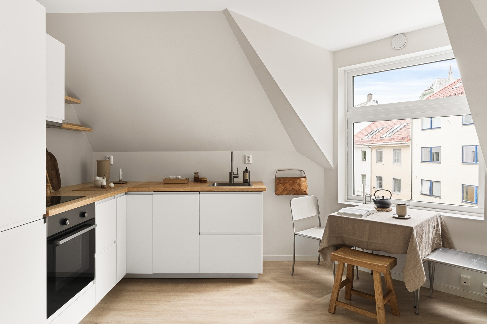 Kjøkkeninnredningen er lys og stilren med slette hvite fronter med integrerte håndtak og benkeplate i laminat. Galleribilde