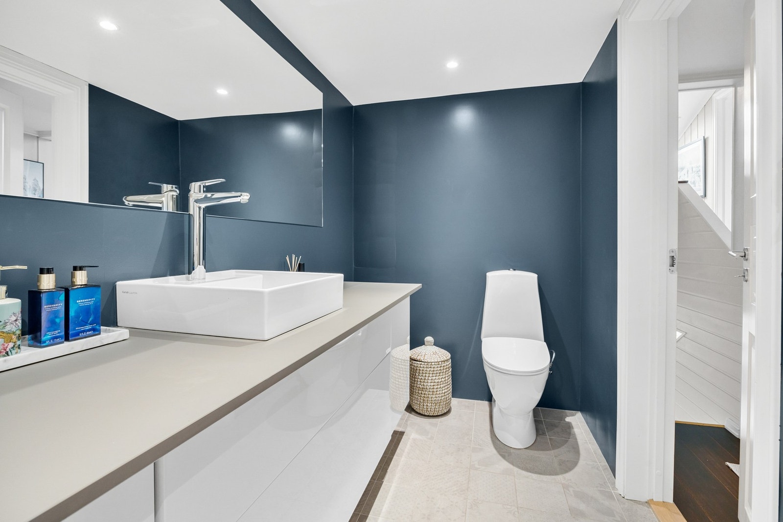 Et moderne bad med toalett, servant og dusjhjørne med glassvegger. Galleribilde