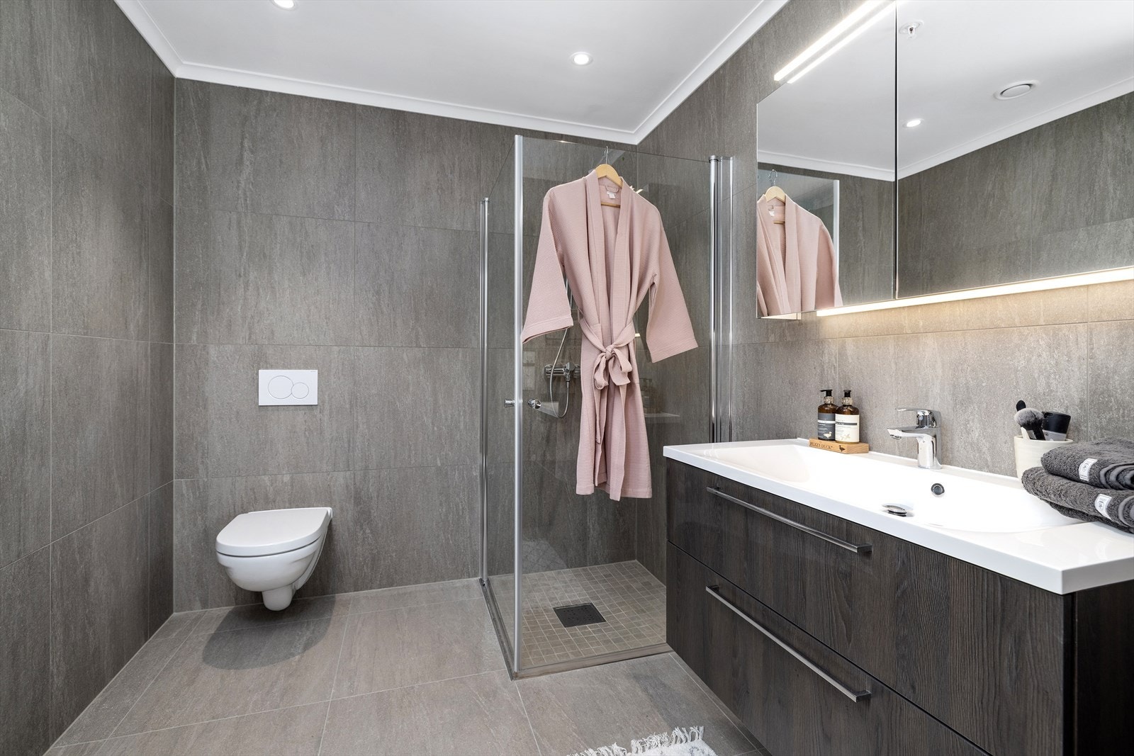 "En suite" bad med mørk innredning fra Sigdal, speilskap med lys, dusjhjørne, downlights i tak og vegghengt toalett Galleribilde