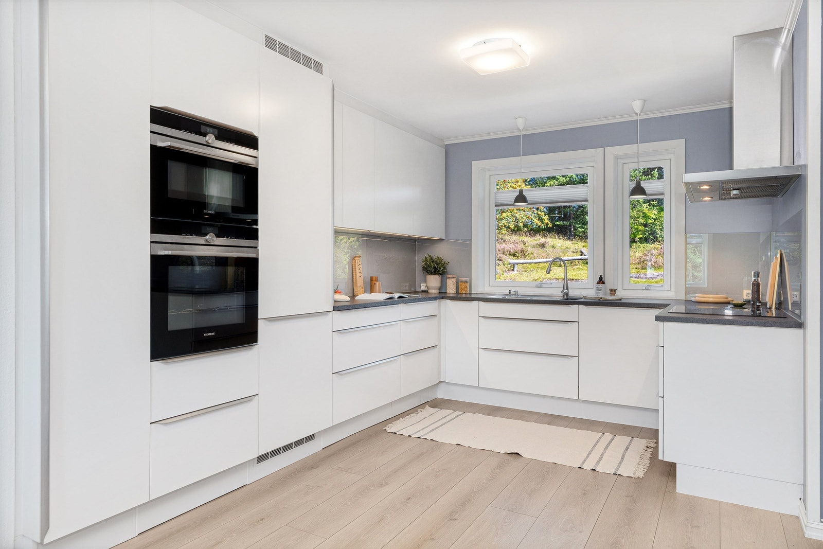 Lekkert og romslig HTH-kjøkken fra 2016 med elegante hvite fronter og en laminat benkeplate. Overbelysning og stikkontakter plassert under overskapene. Galleribilde