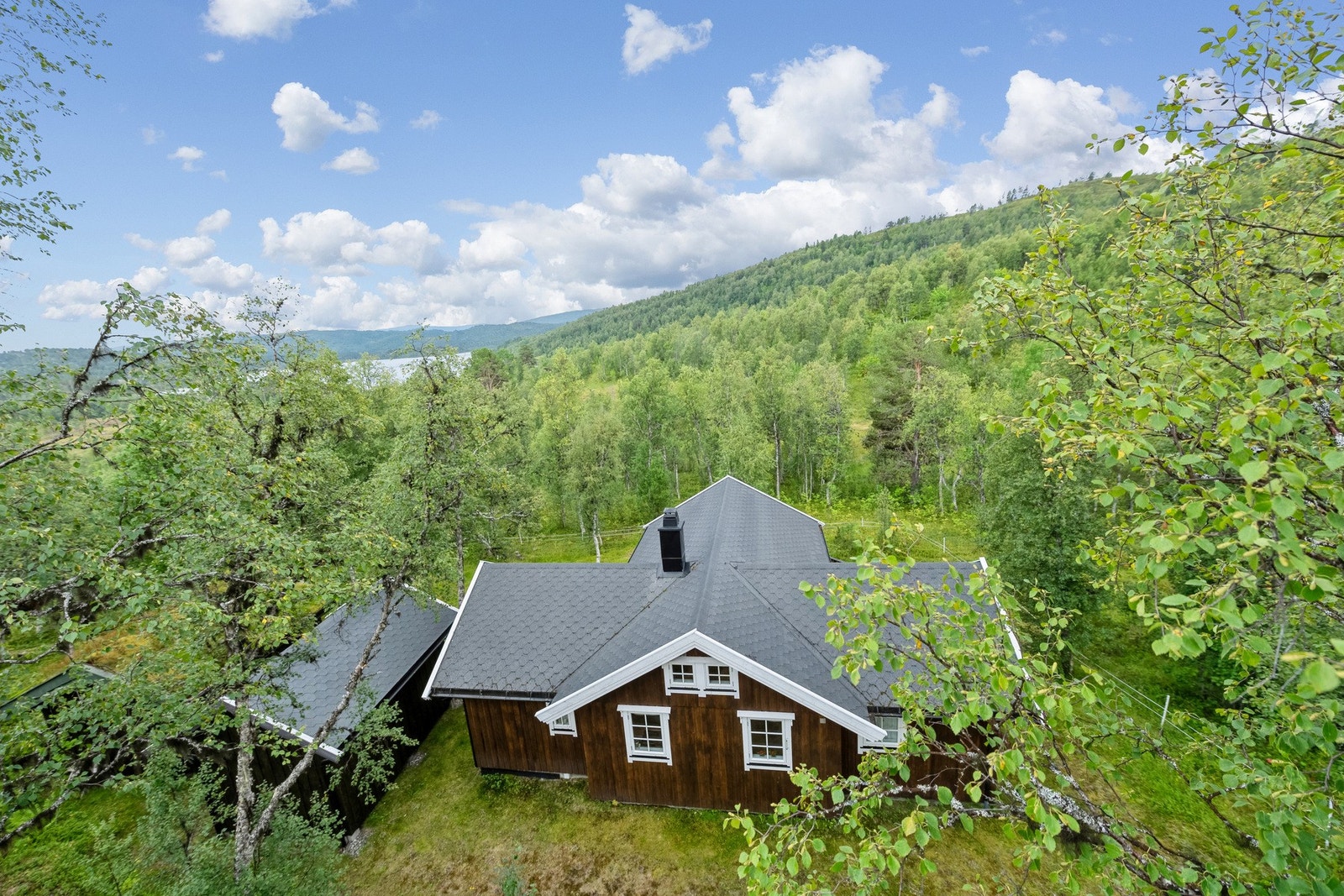 Tomten rammes inn med fjellbjørk, og nærområdet gir assosiasjoner til nasjonalromantiske postkort. Galleribilde