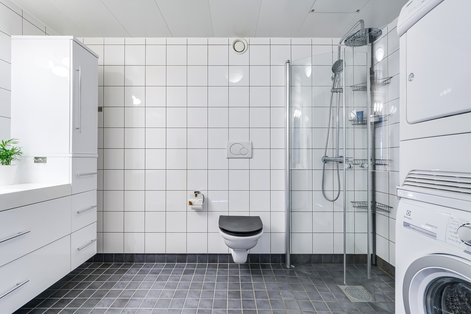Romslig flislagt bad med opplegg for vaskemaskin og tørketrommel. Galleribilde