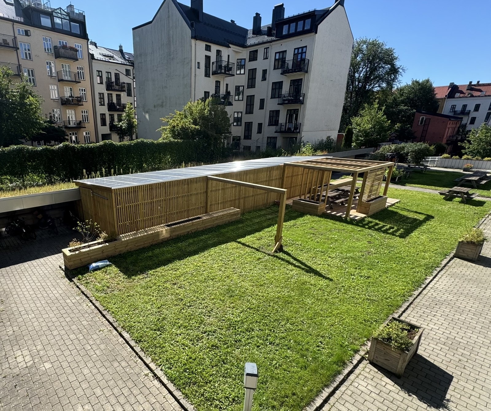 Bakgården ble oppgradert sommeren 2024 med blomsterkasser og sittebenker, pergola og nytt sykkelskur. Galleribilde