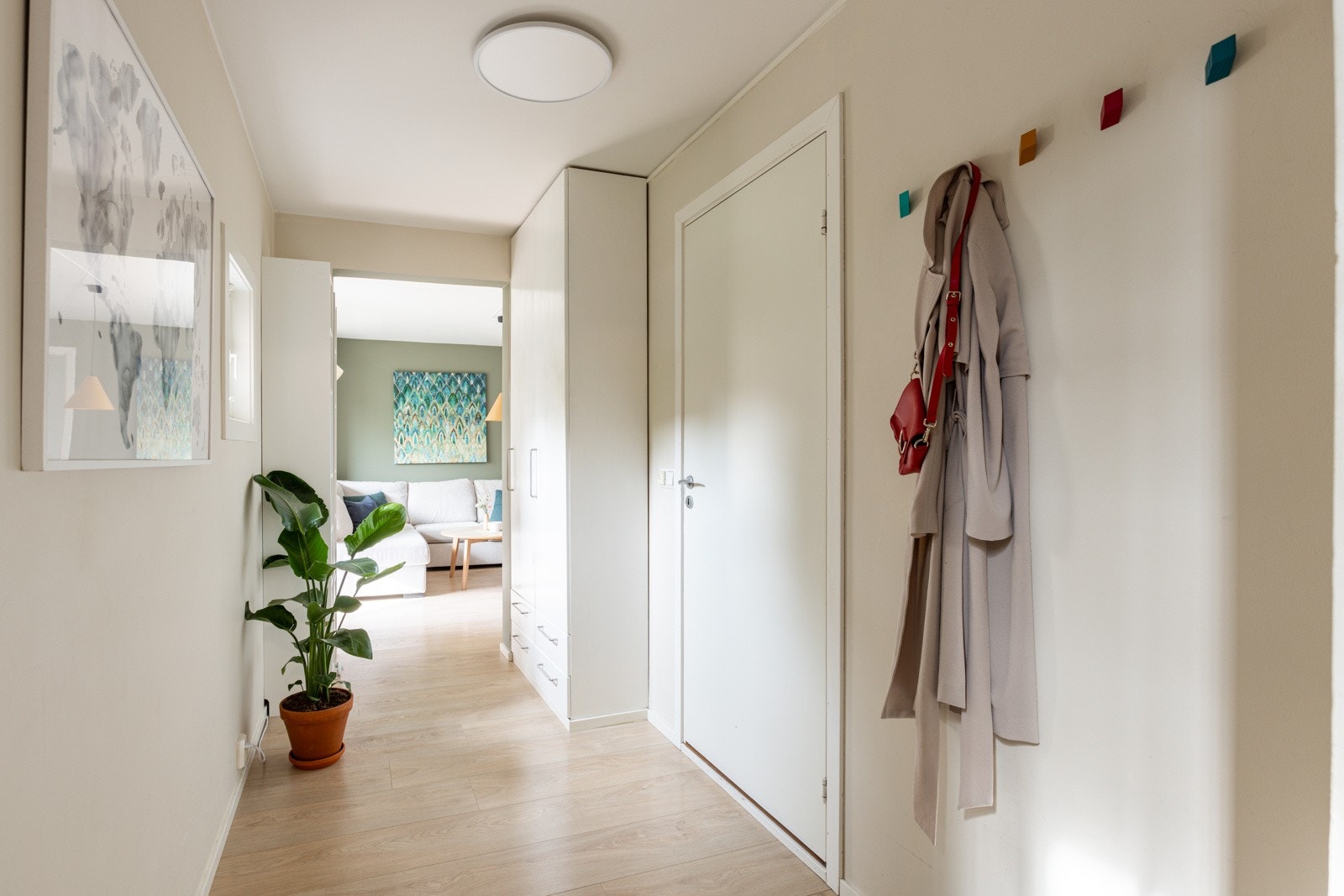 Du ønskes velkommen inn i en lys, romslig og praktisk entré. Entréen har lys enstavs laminat på gulv, overflater malt i en fin lys farge og skjult elektrisk anlegg. Galleribilde