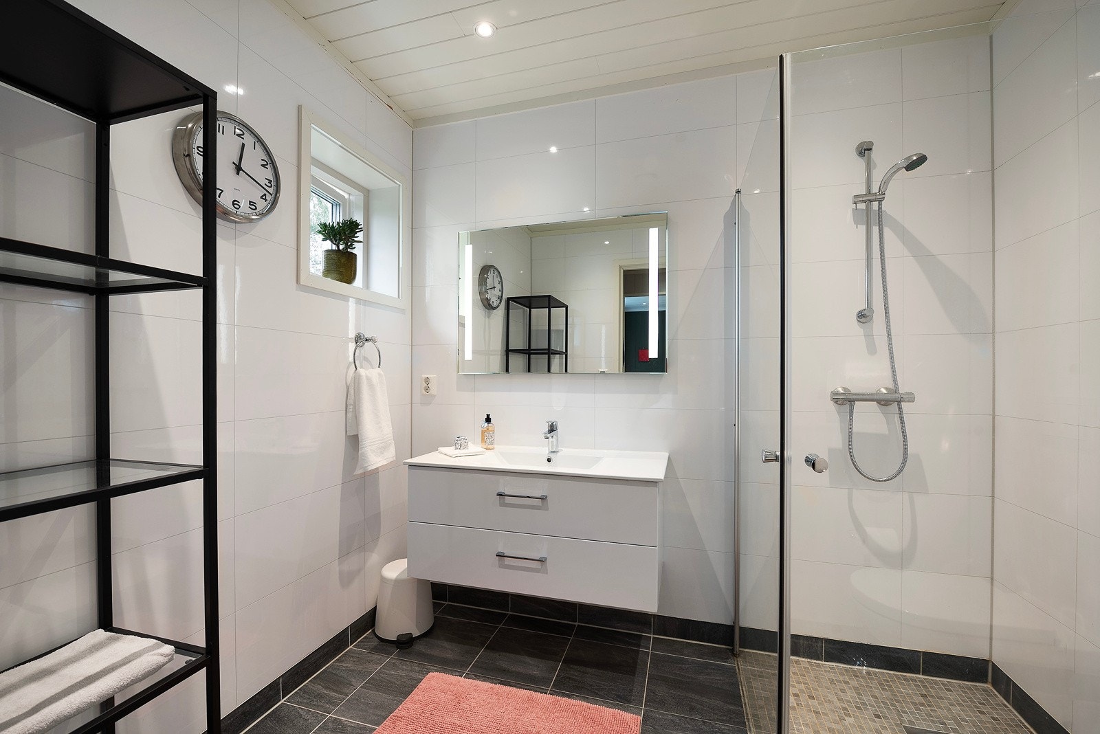 Begge bad har hvit servantinnredning, speil med integrert belysning, veggmontert toalett og dusjhjørne med glassdører Galleribilde