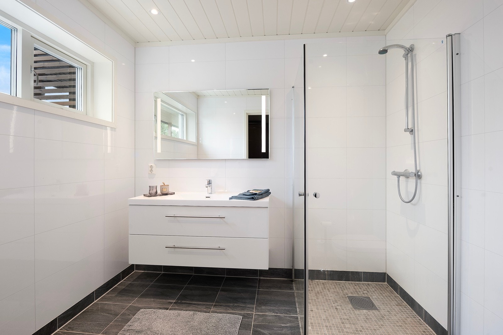 Boligen har to delikate bad med mørke gulvfliser, mosaikk i dusjen og lettstelte baderomsplater på veggene Galleribilde