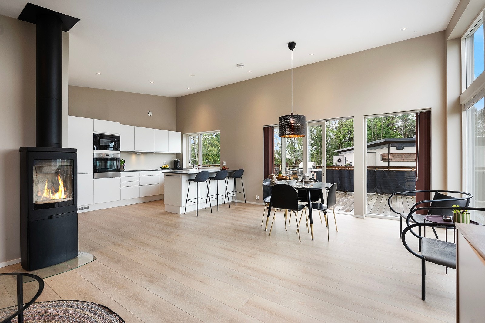 Stuen er lys og åpen med flott takhøyde, store panoramavinduer og hygge fra peisovn Galleribilde