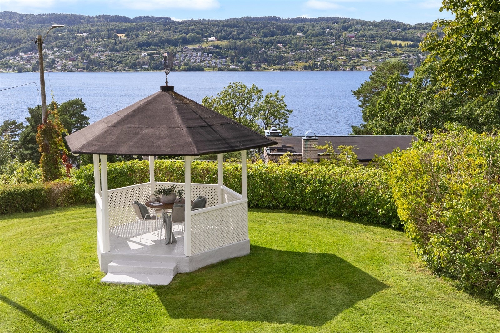 I hagen ligger paviljongen som har plass for hagebord og gir litt skygge på den ellers solrike tomten. Paviljongen er malt i 2024 Galleribilde