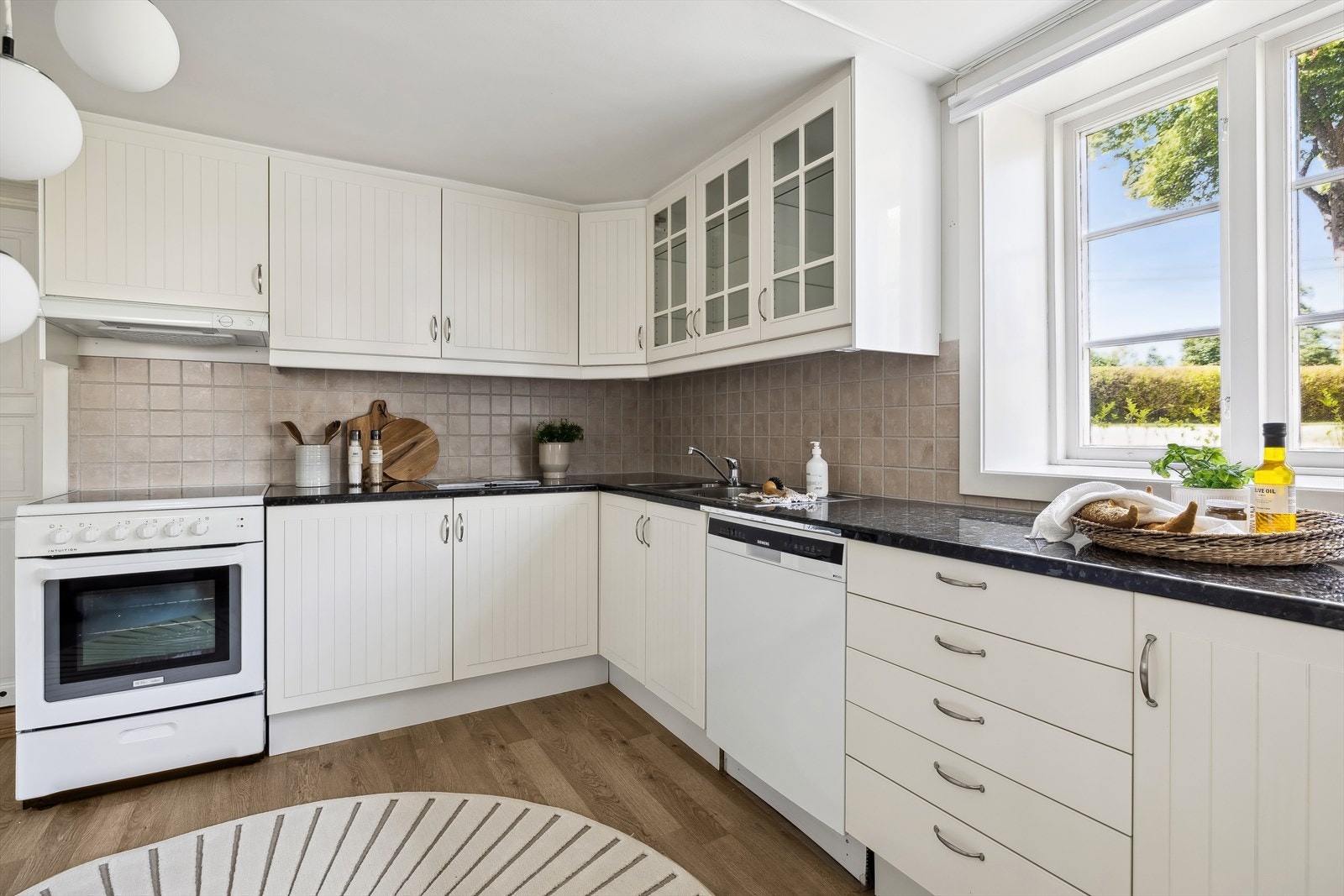 God belysning under overskap til kjøkkenbenken. Det er kjøkkenventilator med avtrekk ut. Galleribilde