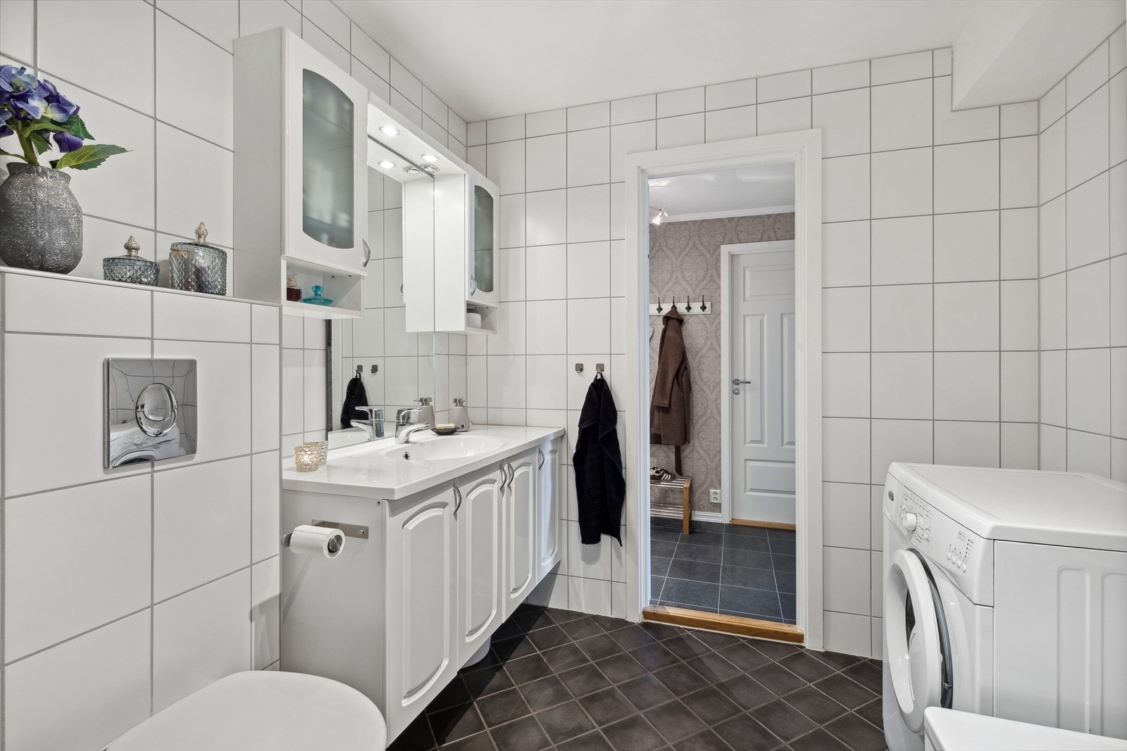 Et tidløst bad med fliser på både gulv og vegger, samt opplegg for vaskemaskin Galleribilde