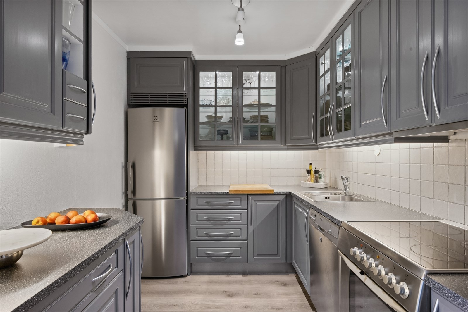 Kjøkkeninnredningen har profilerte fronter, benkeplate av laminat, oppvaskkum og fliser på vegg over benk. Galleribilde