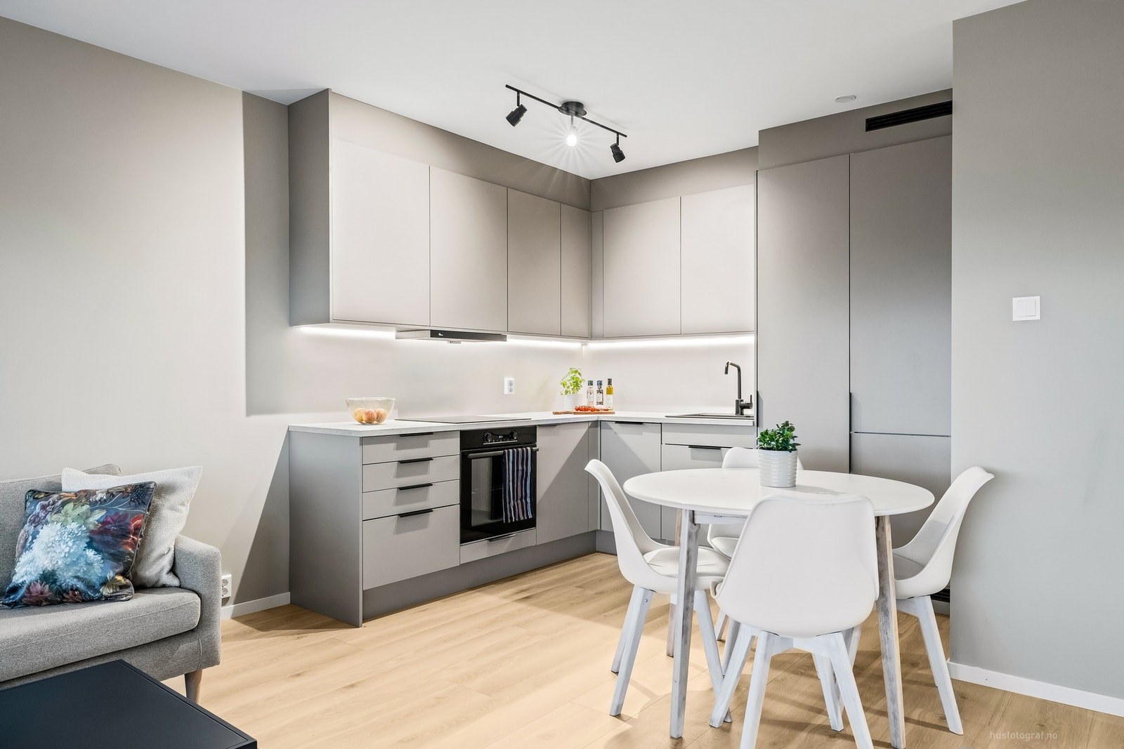 Delikat og tidsriktig kjøkkeninnredning med slette, grå fronter og benkeplate av laminat, samt sorte detaljer som skaper en helhetlig og moderne kontrast. Galleribilde