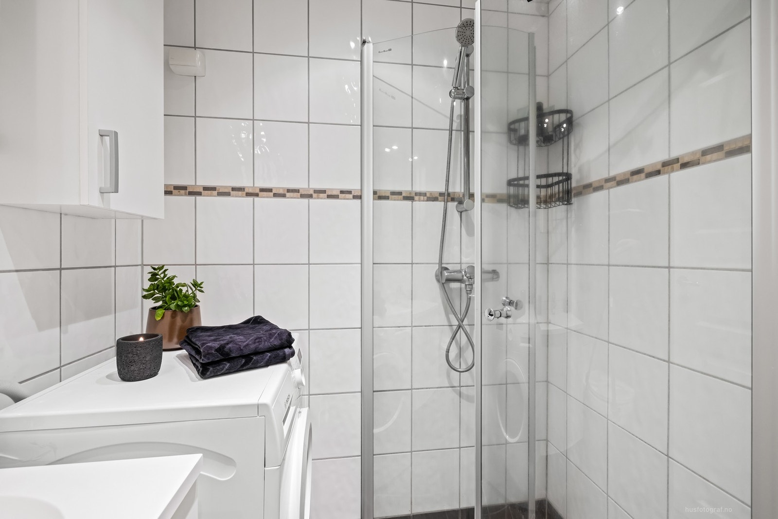 Badet er innredet med vegghengt toalett, enkel servantinnredning med skap, speil med belysning, dusjhjørne og opplegg for vaskemaskin. Galleribilde