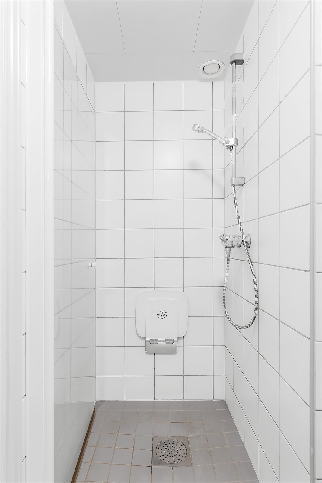 Badet har dusjnisje med veggmontert dusjarmatur og dusjdør av glass Galleribilde