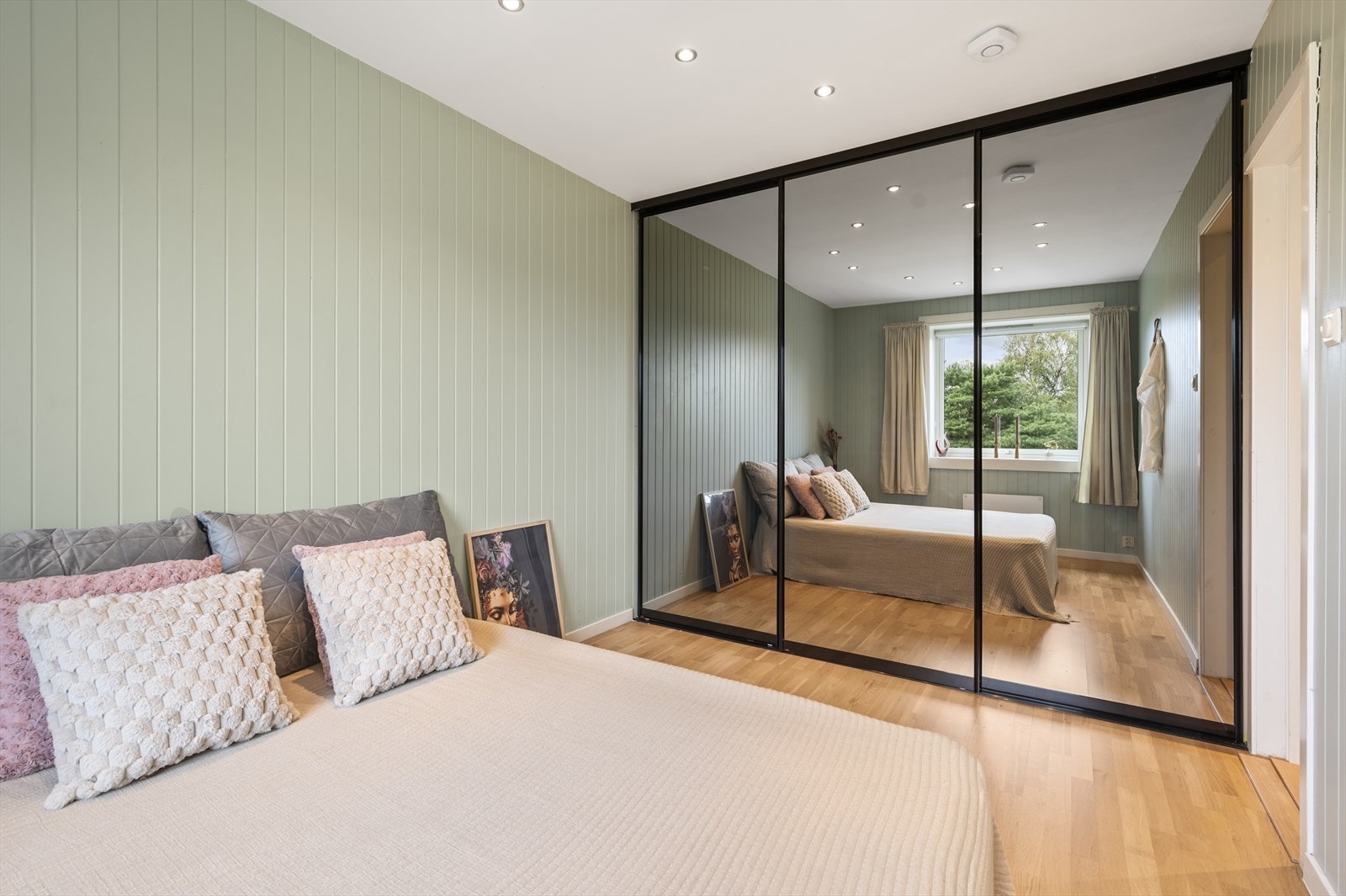 Det er god plass til dobbeltseng og nattbord, og rommet har en stor skyvedørsgarderobe med speilfronter for praktisk oppbevaring Galleribilde