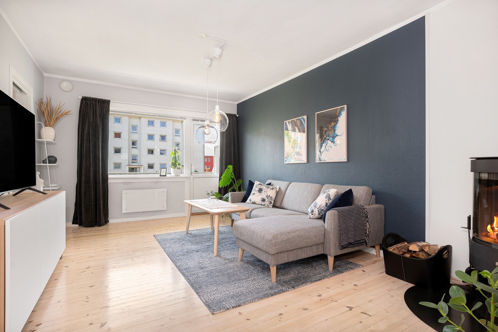 Stor stue med en pen sofa og en koselig nyere vedovn. Galleribilde
