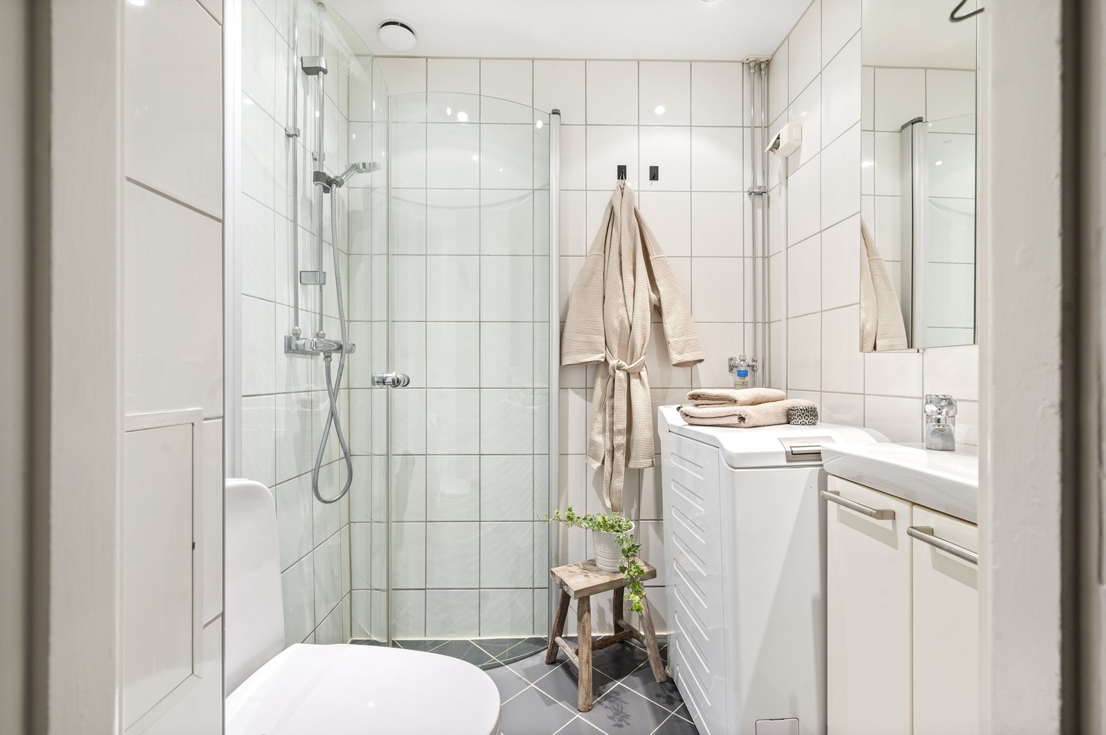 Baderomsinnredningen består av servant med underskap, speilskap, frittstående toalett og dusjnisje med svingbare glassdører. Galleribilde