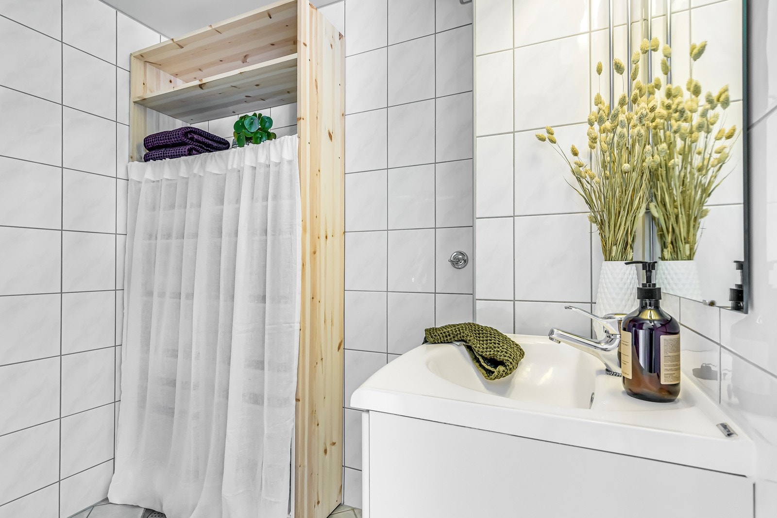 Baderommet inneholder vegghengt servantskap, speil med overlys samt stikkontakt og dusjhjørne med innfellbare glassdører. Galleribilde