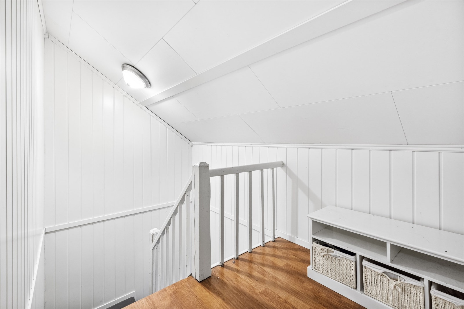 Gang oppe i 2. etasje med hvitmalt panel på veggene og laminat på gulvet. Galleribilde