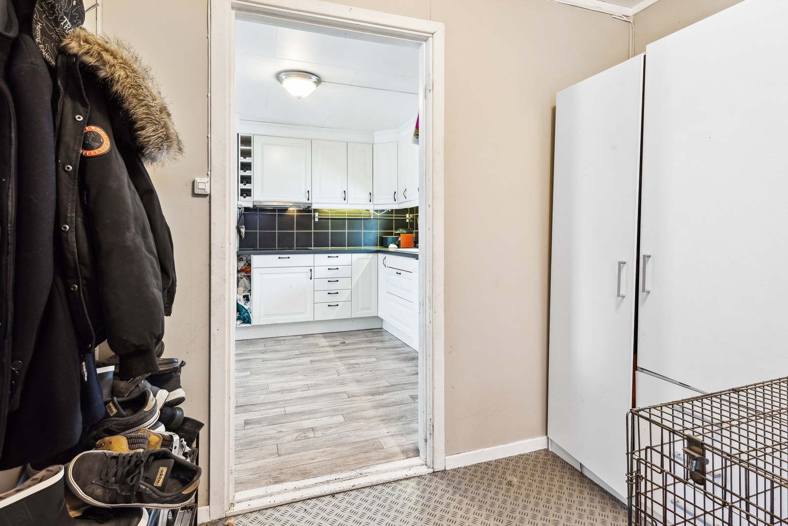 Her kommer man inn i en entré med sandfargede vegger og belegg på gulvet. Entréen er romslig med god plass til å etablere garderobeskap og annet møblement til å henge fra seg yttertøyet. Galleribilde