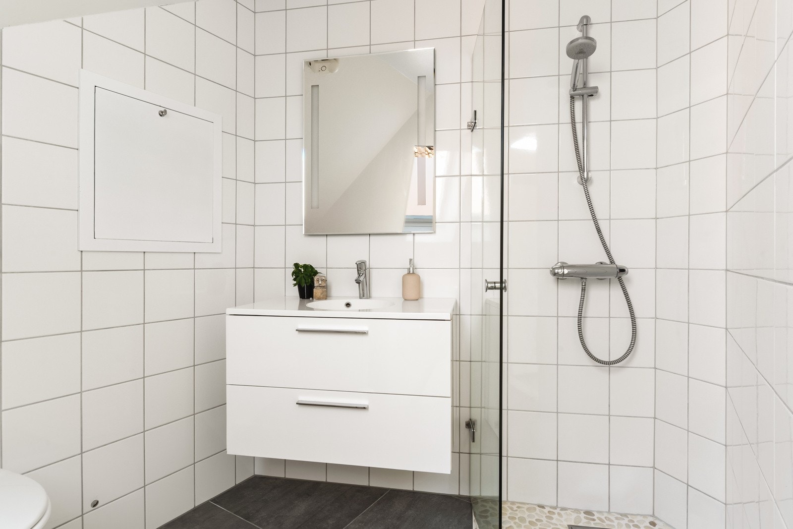 Badet er helfliset og har en slett malt himling med innfelte downlights i himling og varmekabler i gulv. Galleribilde
