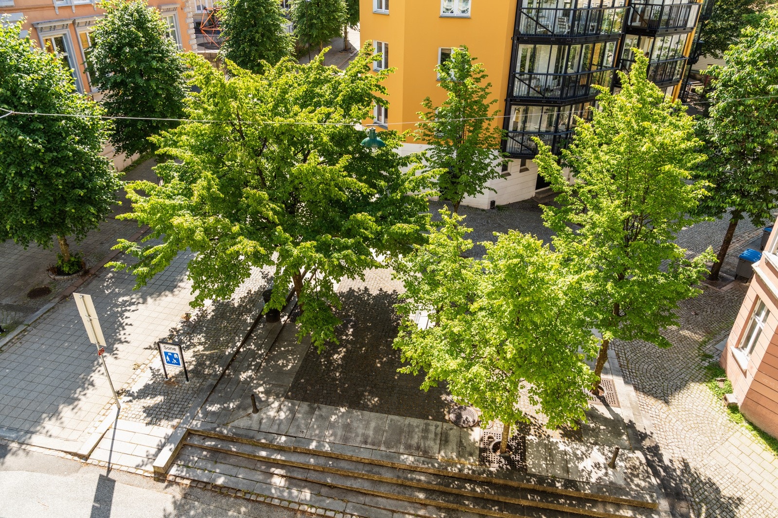 Fra boligen ser du ned på et bilfritt gatetun med flott beplantning. Galleribilde