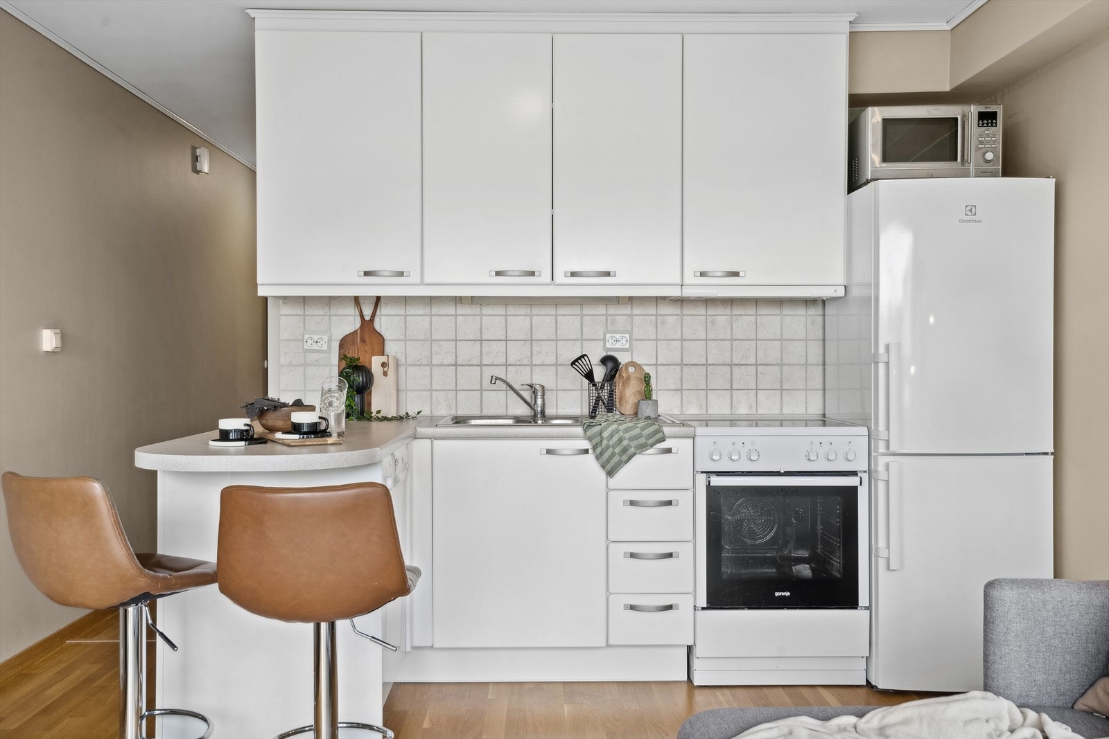 Kjøkken i hvite glatte fronter, samt flislagt vegg over benkeplate. Plass til frittstående kjøl/frys, komfyr og oppvaskmaskin. Galleribilde
