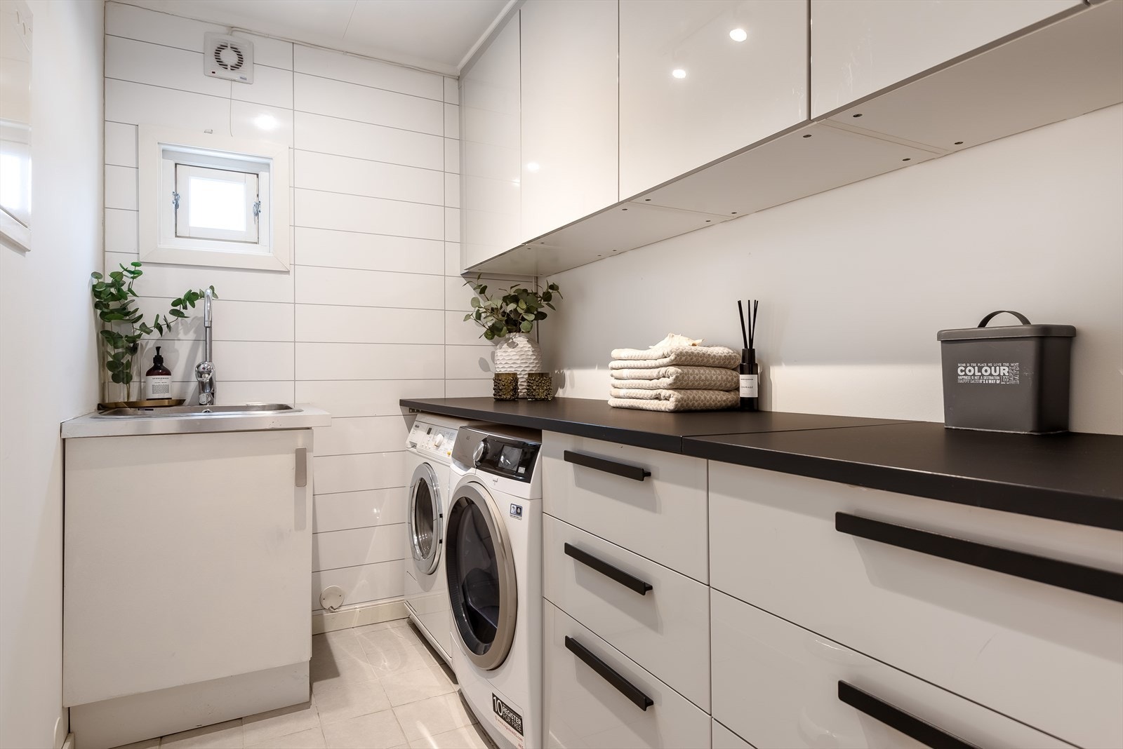 Vaskerom med god oppbevaringsplass og innebygd område for vaskemaskin og tørketrommel Galleribilde