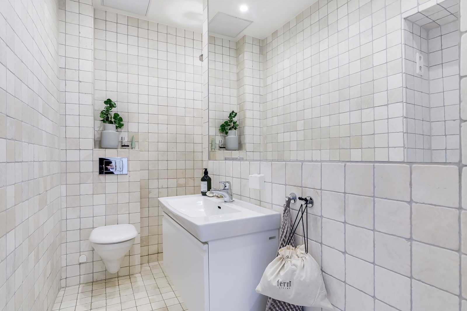 Badet er innredet med lyse fliser på vegger og gulv, som gir et tidløst uttrykk Galleribilde