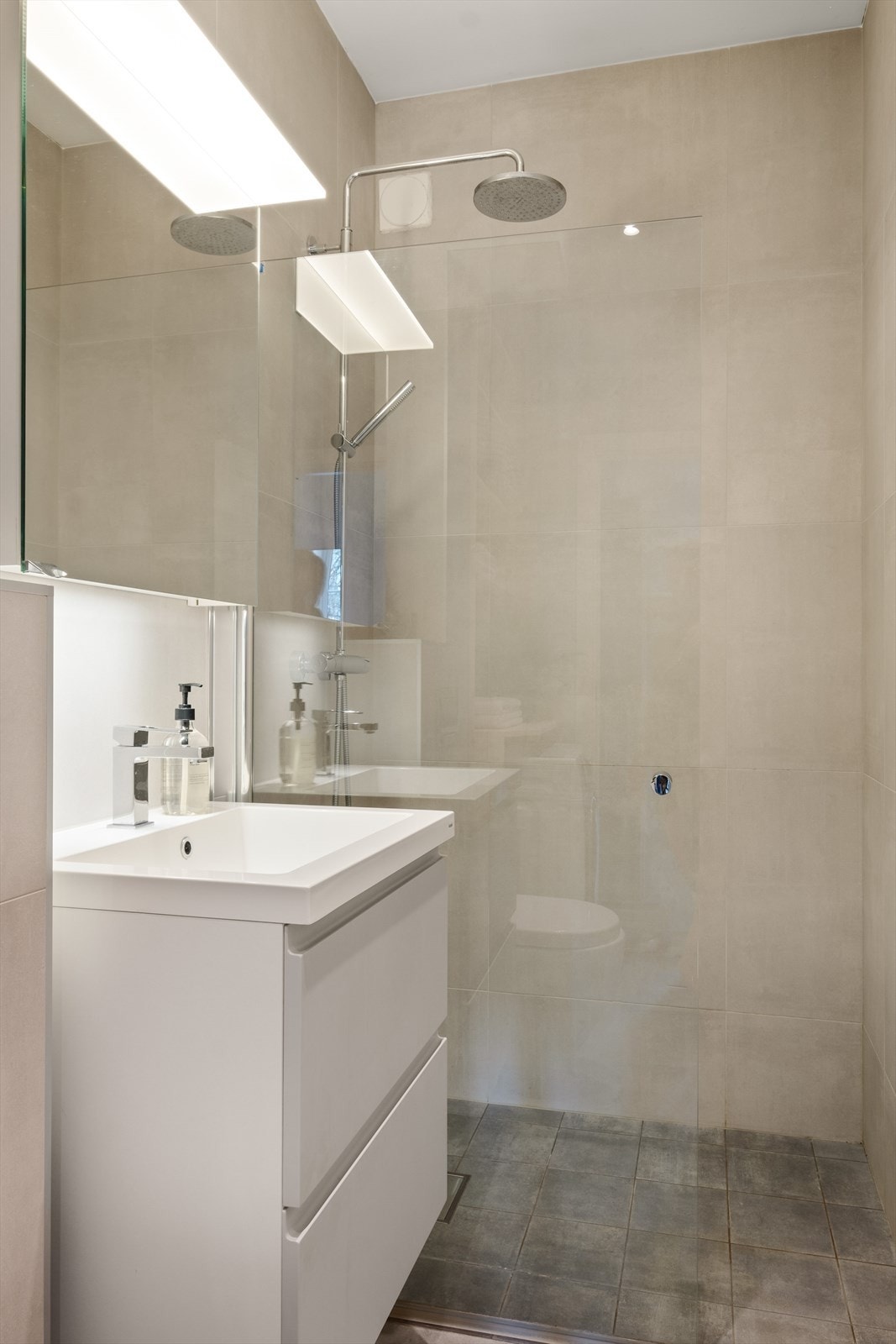 Innerst i rommet finner man en dusjnisje med regnfalssdusj og håndholdt spylefunksjon. Det er sluk fra 2016 i dusjen og det ble påvist en banemembran og klemring i sluket. Galleribilde