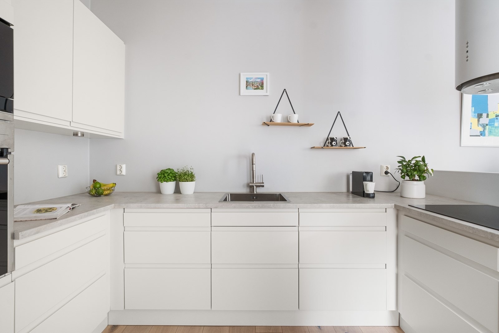 Kjøkkeninnredning med laminerte benkeplater, slette fronter, malt backsplash og ventilator med kullfilter. Galleribilde