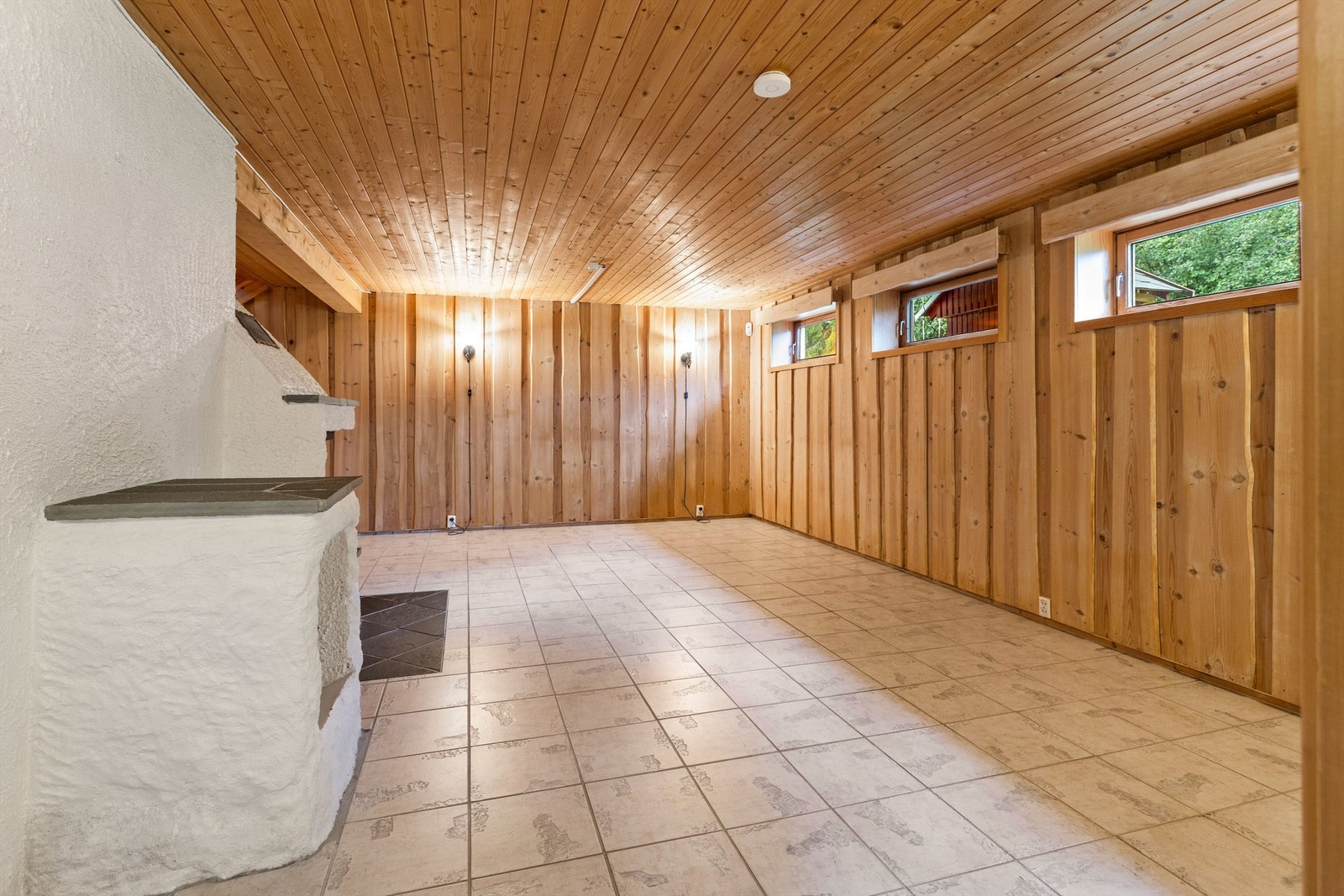 Disponibelt rom i kjelleren har lyse fliser på gulvet og tømmermannspanel på veggene. Galleribilde