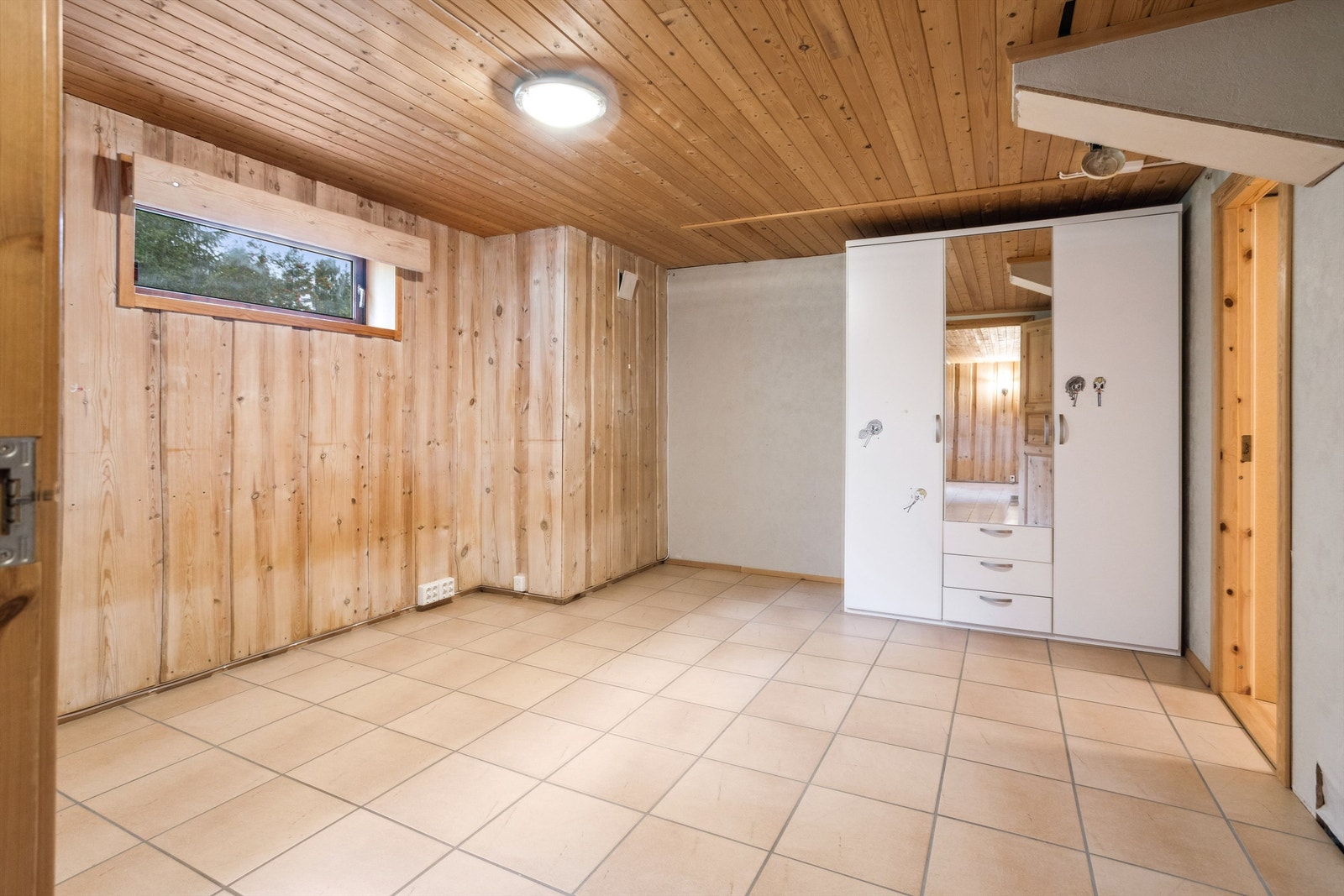 Dette rommet har lyse fliser på gulvet, og tømmermannspanel og lysmalt strie/tapet på veggene. Rommet er innredet med garderobeskap, men er ikke godkjent til varig opphold. Galleribilde